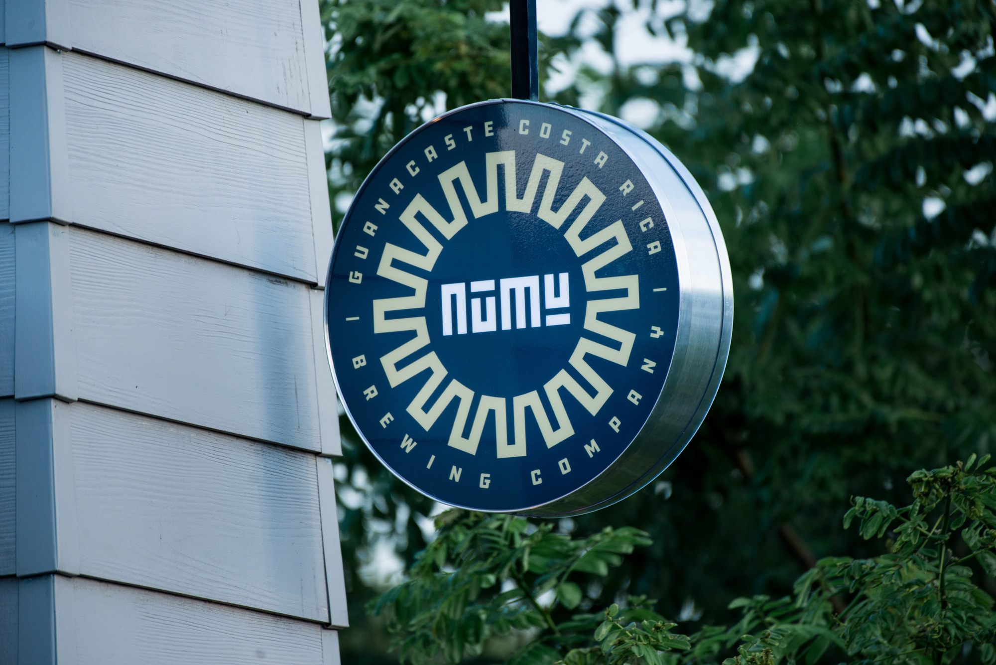 Corporeo circular con Logo Numu detrás de un follaje verde